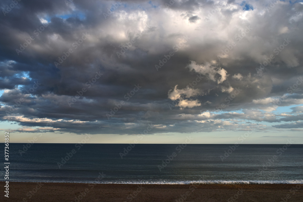 Beach in front of the sea with sky with stormy clouds in the afternoon