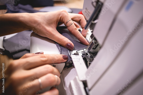 Close up of seamstress holding cloth while working on sewing machine 