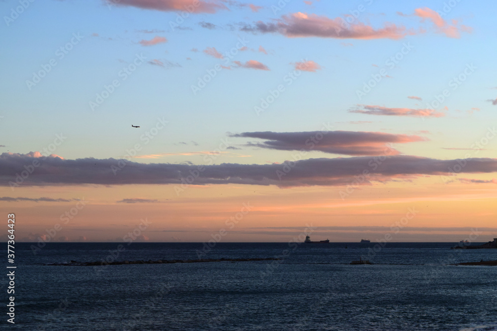 Sea view with sunset sky with ships and plane in the distance