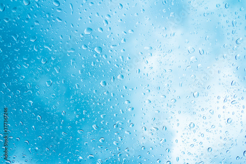 Blue water drops on glass or rain drop background 