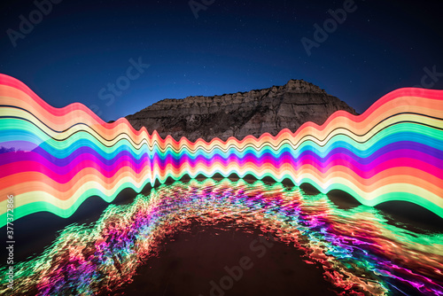 Light Painted Rainbow and Reflection. Trippy Night Photography in a River, in Front of a Mountain