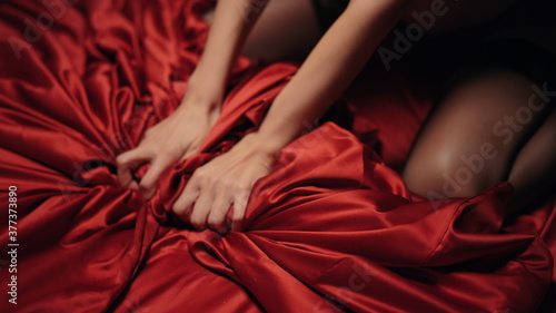 Woman hands touching red silk sheet indoors. Slim woman squeezing satin cover.