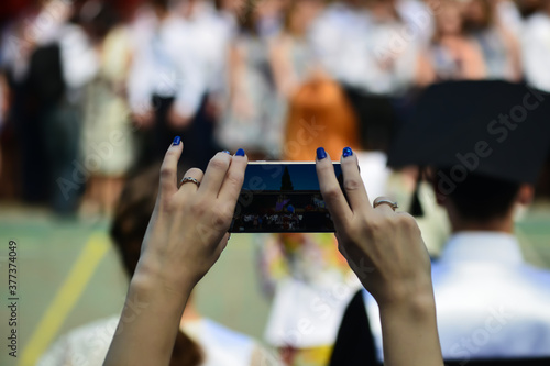 Woman using smartphone taking picture at graduation party