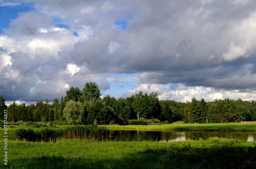 Black storm clouds during summer, Landscape with trees and meadows in the foreground in Latvia. Low clouds