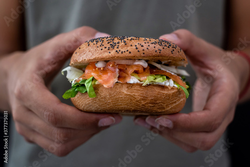 Woman holding a lox bagel with cream cheese and veggies
