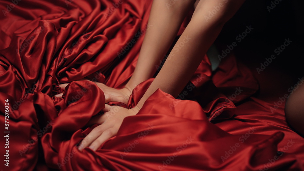 Woman hands holding red satin sheet on bed. Unknown girl having moment pleasure. Woman hands holding red satin sheet on bed. Unknown girl having moment pleasure.