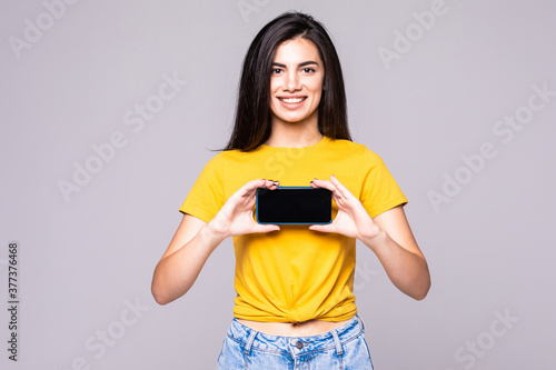 Portrait of a woman showing blank smartphone screen over gray background