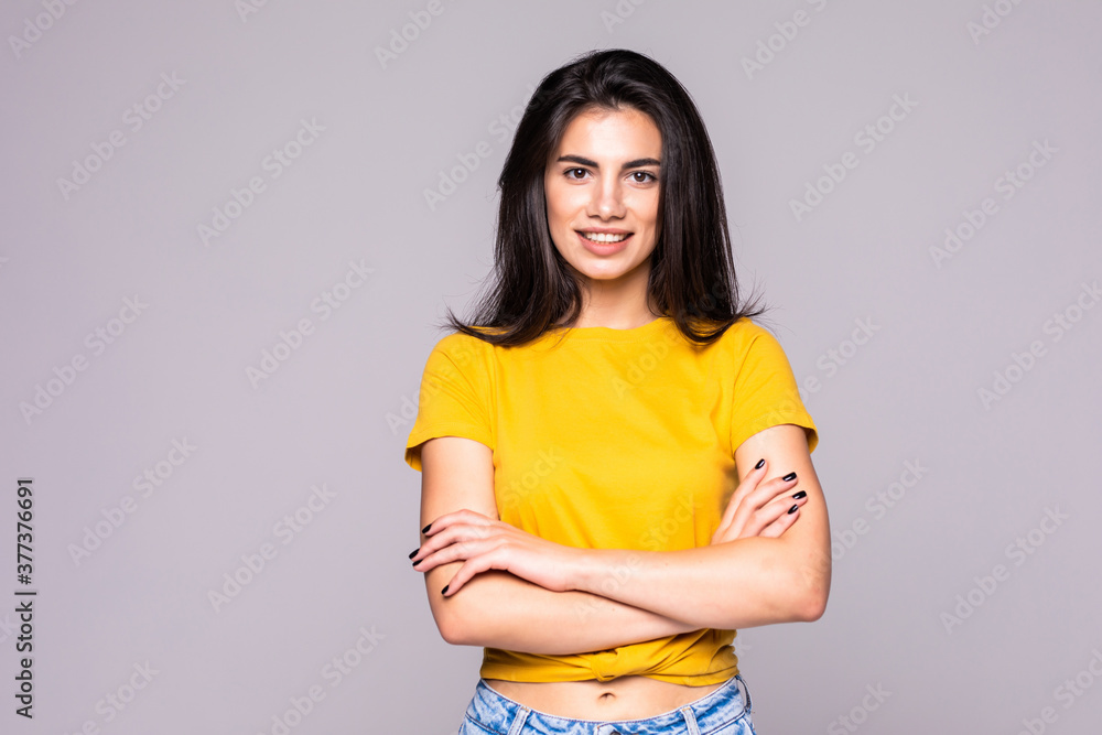 Portrait of a cheerful smiling woman standing with arms folded isolated on the gray background Portrait of a cheerful smiling woman standing with arms folded isolated on the gray background