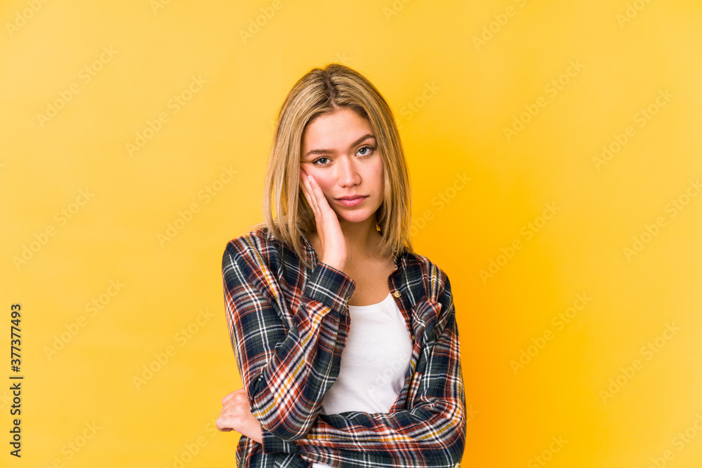 Young blonde caucasian woman isolated on a yellow background who is bored, fatigued and need a relax day. Young blonde caucasian woman isolated on a yellow background who is bored, fatigued and need a relax day.