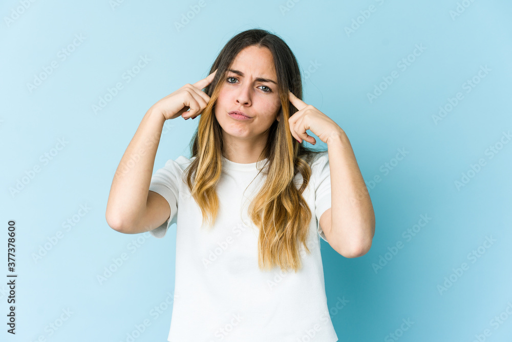 Young caucasian woman isolated on blue background focused on a task, keeping forefingers pointing head. Young caucasian woman isolated on blue background focused on a task, keeping forefingers pointing head.
