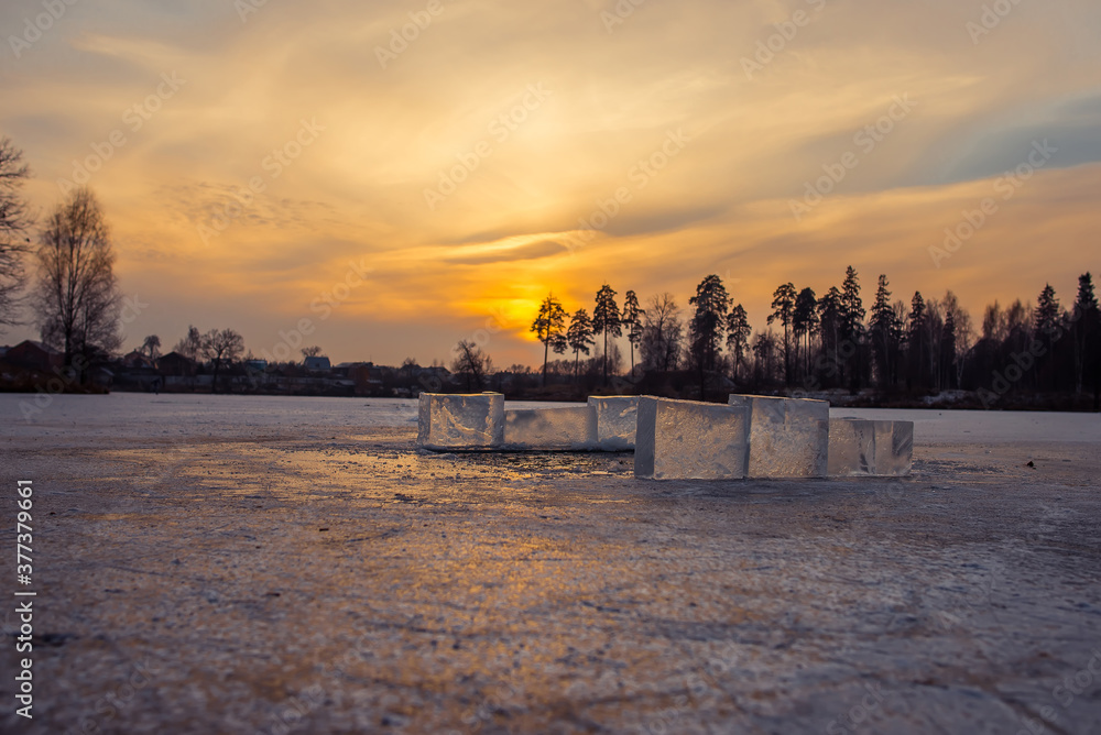 Transparent ice cubes on the lake at sunset background
