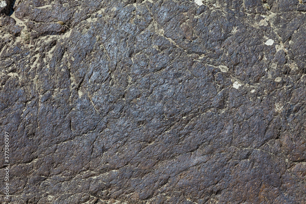 A large layer of rock close-up of a smooth gray stone with cracks. Background for wallpaper, post or illustrations in social networks.
