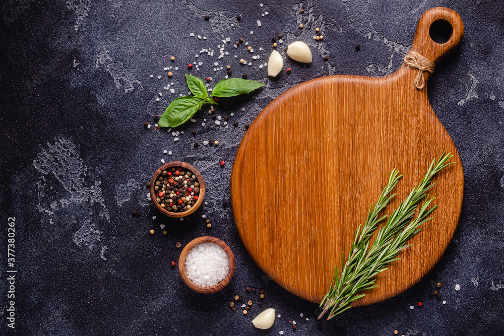 Herbs and condiments on black stone background.