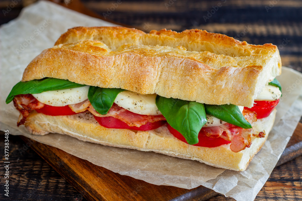 Caprese sandwich with tomatoes, mozzarella, basil and bacon. Healthy eating. Italian cuisine. Caprese sandwich with tomatoes, mozzarella, basil and bacon. Healthy eating. Italian cuisine.