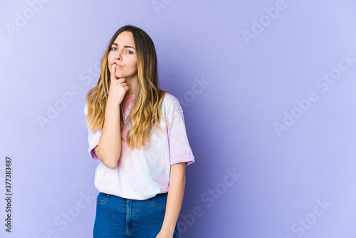 Young caucasian woman isolated on purple background thinking and looking up, being reflective, contemplating, having a fantasy.