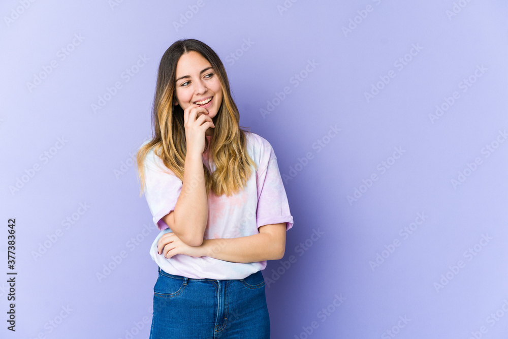 Young caucasian woman isolated on purple background relaxed thinking about something looking at a copy space. Young caucasian woman isolated on purple background relaxed thinking about something looking at a copy space.