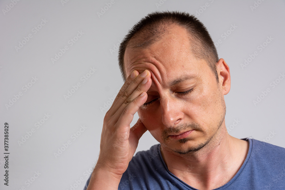 showing how much his head hurts, experiencing pain, looking miserable and exhausted showing how much his head hurts, experiencing pain, looking miserable and exhausted