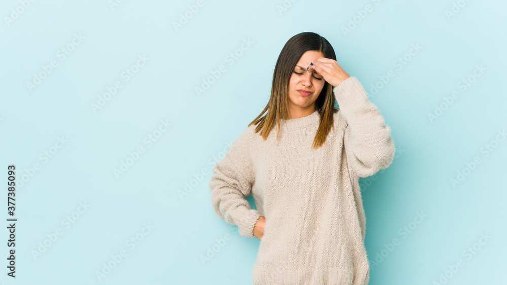 Young woman isolated on blue background having a head ache, touching front of the face. Young woman isolated on blue background having a head ache, touching front of the face.
