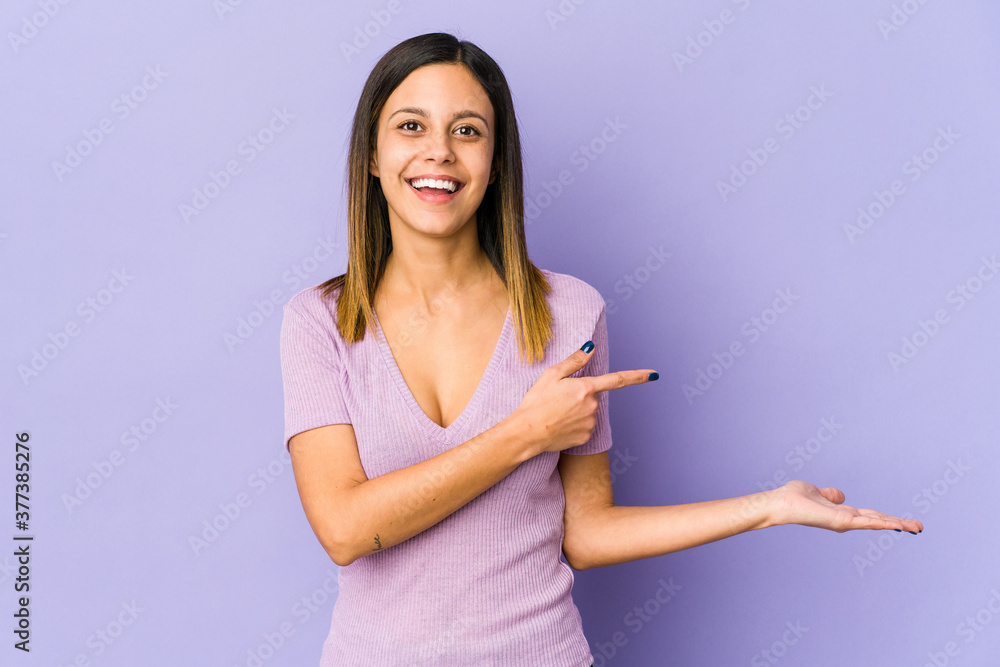 Young woman isolated on purple background excited holding a copy space on palm. Young woman isolated on purple background excited holding a copy space on palm.