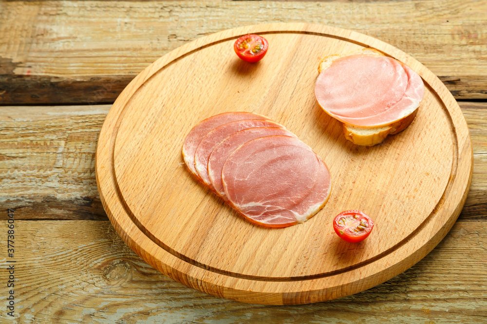 Ham sliced on a wooden board on the table.