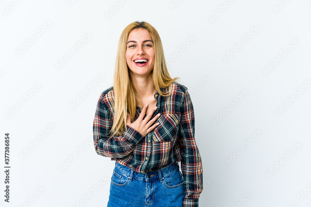 Young blonde woman isolated on white background laughs out loudly keeping hand on chest. Young blonde woman isolated on white background laughs out loudly keeping hand on chest.