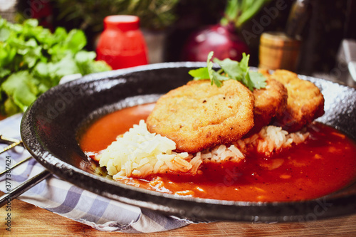 Tortas de papa fritas sobre arroz y salsa picante de tomate, una comida de México.