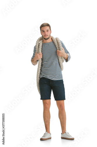 Pulls the rope, tug of war. Caucasian male sailor in uniform on white studio background. Young man using modern devices and gadgets. Concept of tech, professional occupation, job of seaman, emotions.