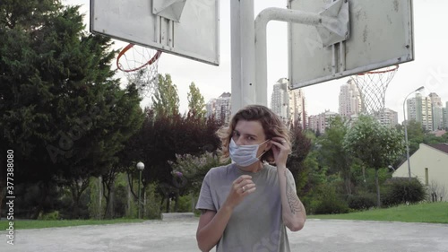 Woman wears a medical mask while walking in the park during the coronavirus pandemic.