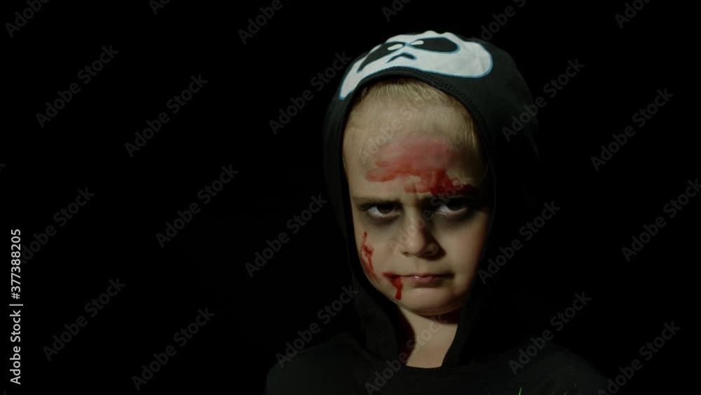 Halloween, angry girl with blood makeup on face. Kid dressed as scary skeleton, posing, making faces Halloween, angry girl with blood makeup on face. Kid dressed as scary skeleton, posing, making faces