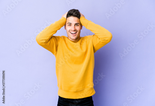 Young caucasian man isolated on purple background screaming, very excited, passionate, satisfied with something. © Asier