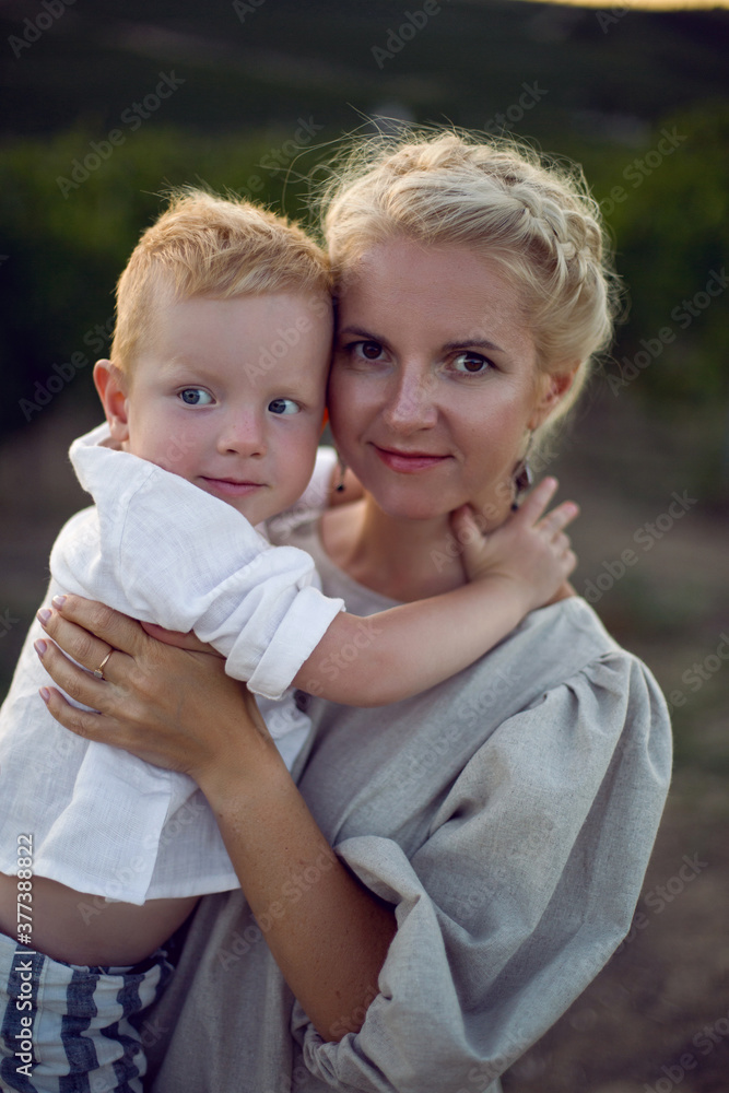 Fototapeta premium blonde woman in a dress holds her baby boy in her arms