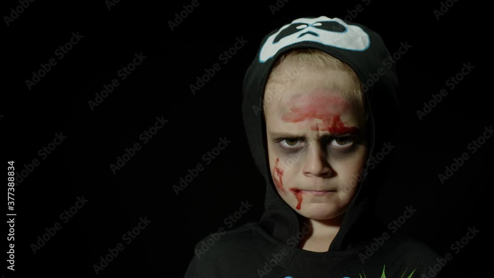 Halloween, angry girl with blood makeup on face. Kid dressed as scary skeleton, posing, making faces Halloween, angry girl with blood makeup on face. Kid dressed as scary skeleton, posing, making faces