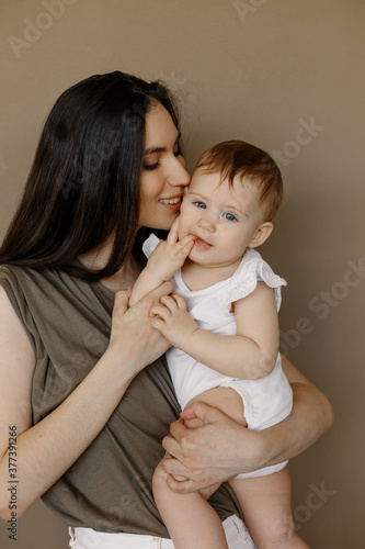 Woman in light clothes have fun with cute child baby girl. Mother  little kid daughter isolated on pastel wall background  studio portrait. Mother s Day love family  parenthood childhood concept