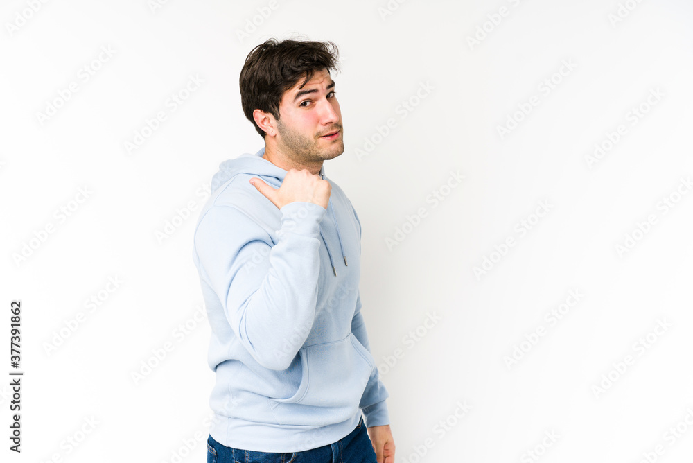 Young man isolated on white background points with thumb finger away, laughing and carefree. Young man isolated on white background points with thumb finger away, laughing and carefree.
