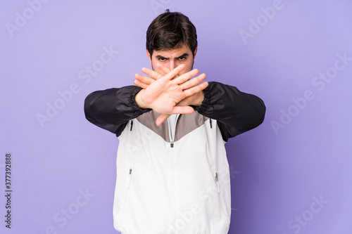 Young man isolated on purple background doing a denial gesture © Asier