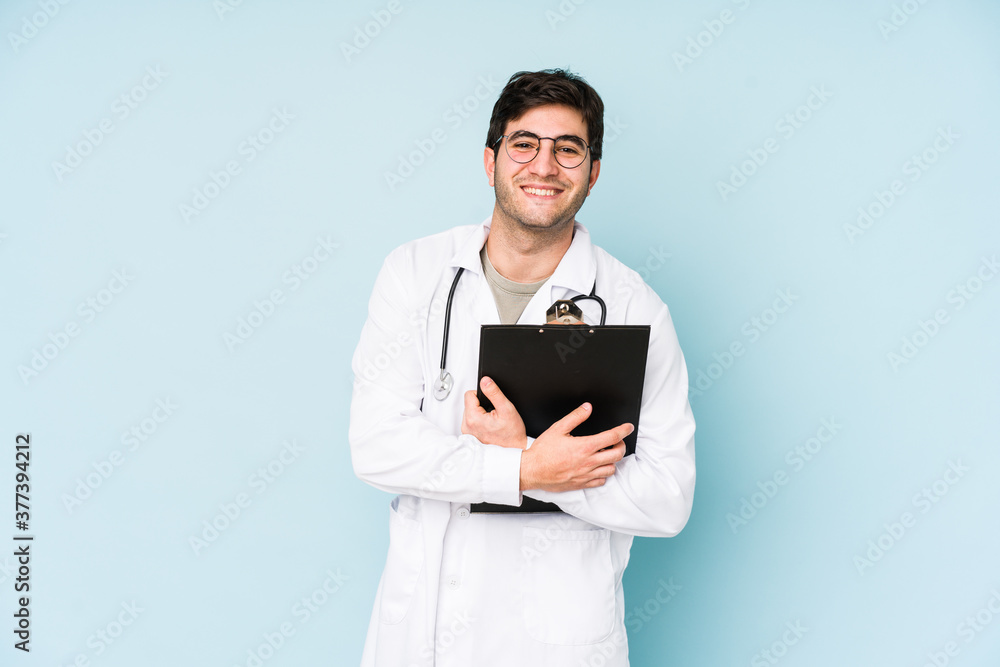 Young doctor man isolated on blue background laughing and having fun. Young doctor man isolated on blue background laughing and having fun.