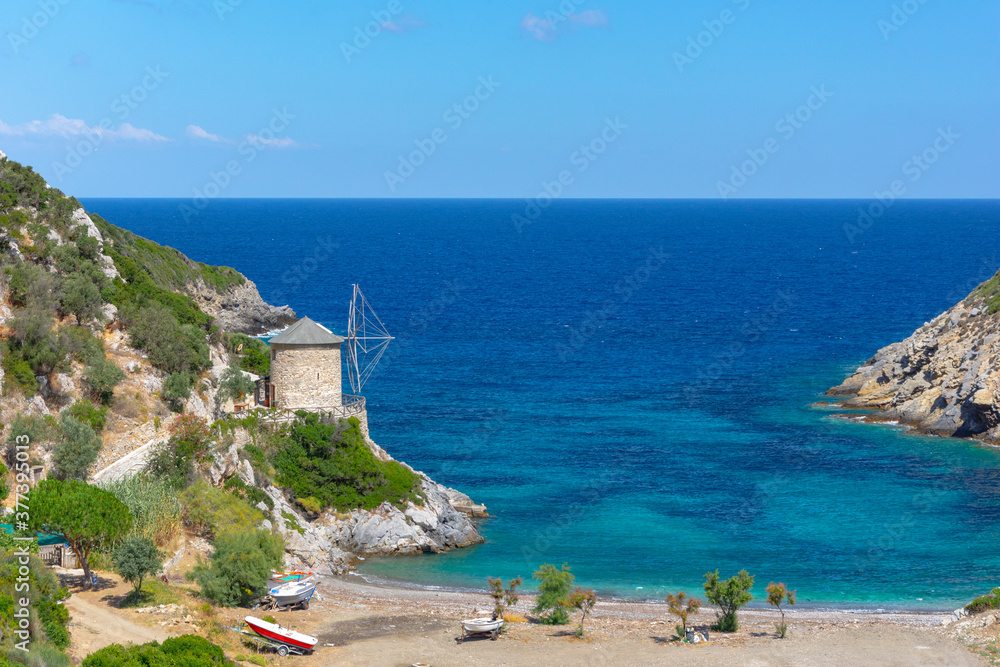 Gialia beach with old windmill in Alonnisos island, Greece.