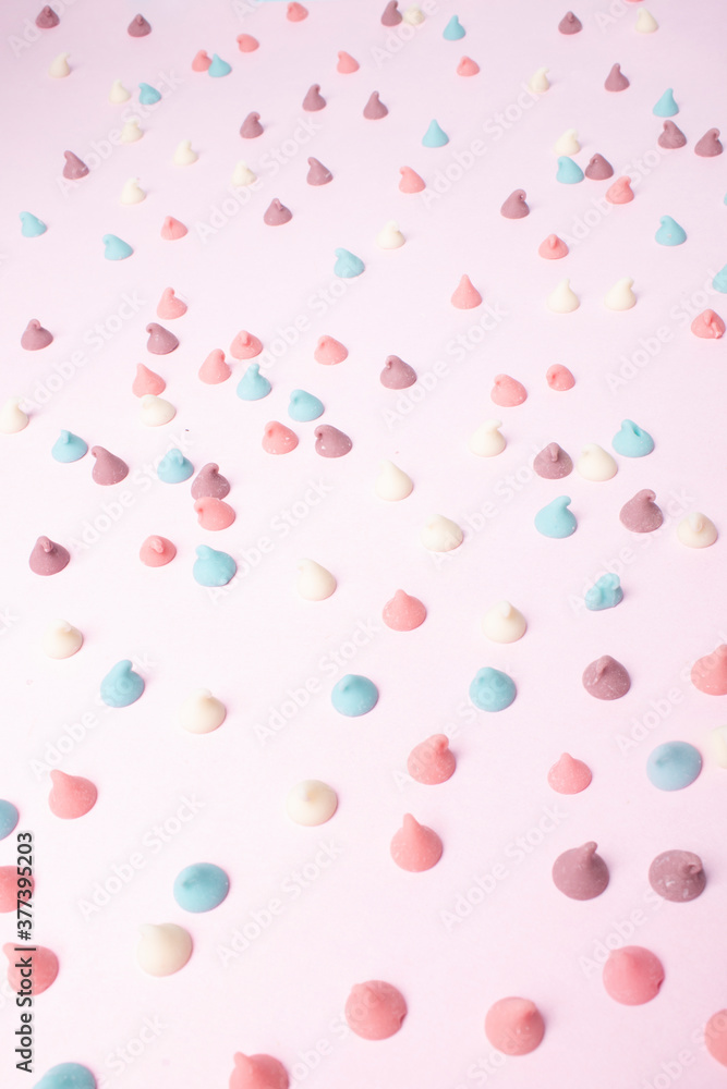 background candy sweets or pastel chocolate chips on a pink background that form a nice texture