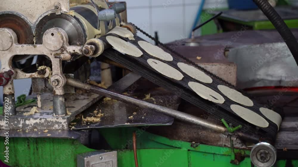 Tortillas stamped out into perfect circles move down a conveyor belt towards the oven where they are cooked. Tortillas stamped out into perfect circles move down a conveyor belt towards the oven where they are cooked.
