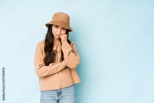 Young indian woman wearing a hat isolated on blue background who feels sad and pensive, looking at copy space.