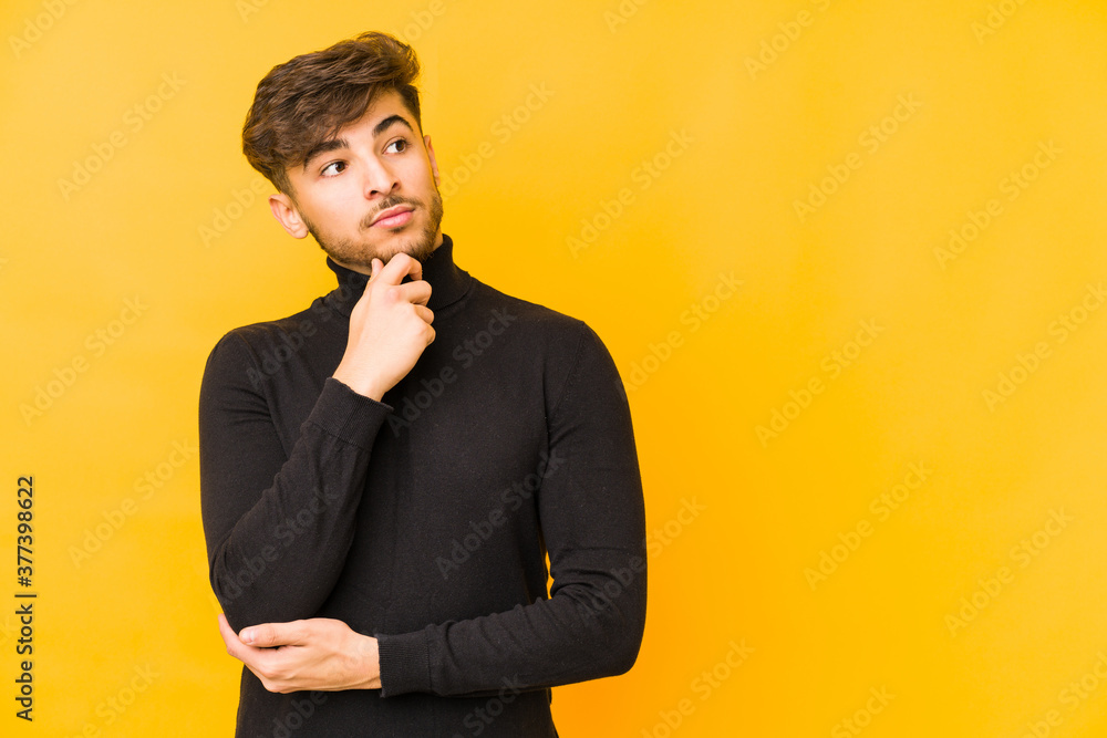 Young arabian man isolated on a yellow background looking sideways with doubtful and skeptical expression. Young arabian man isolated on a yellow background looking sideways with doubtful and skeptical expression.