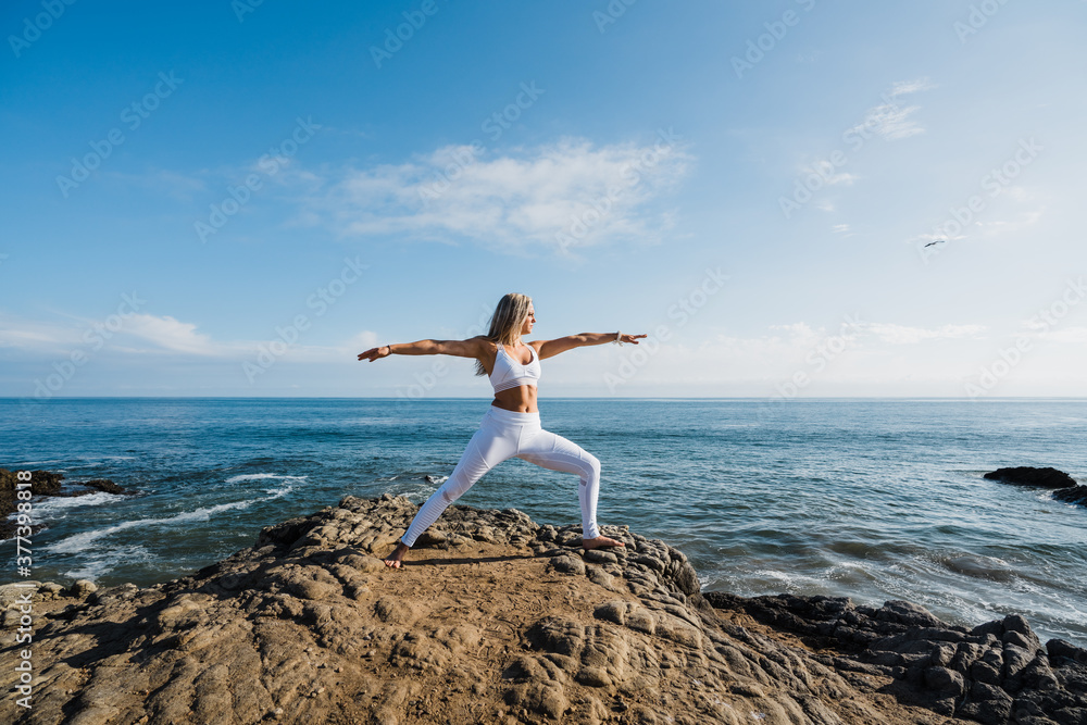 young woman doing yoga exercises on the rocky beach young woman doing yoga exercises on the rocky beach
