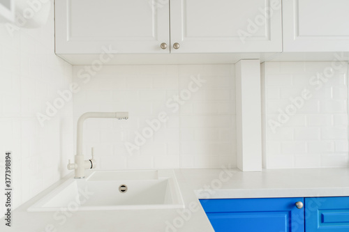 A modern bright kitchen with white and blue wardrobe.