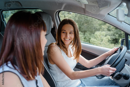 Two happy young women friends are driving a car and enjoy the company. T © Med Photo Studio