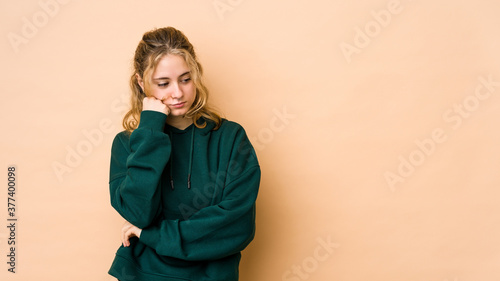 Young caucasian woman isolated on beige background who feels sad and pensive, looking at copy space. © Asier
