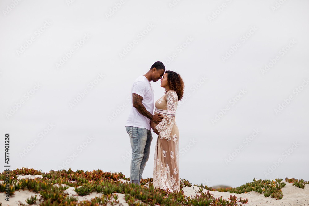 Mixed Race Couple Embracing on Sand Dunes Maternity Mixed Race Couple Embracing on Sand Dunes Maternity