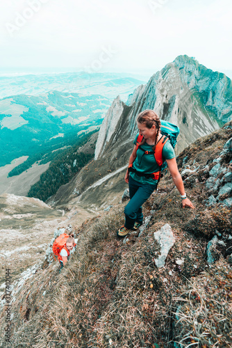 Two active female climbers ascending steep grass mountain in CH photo