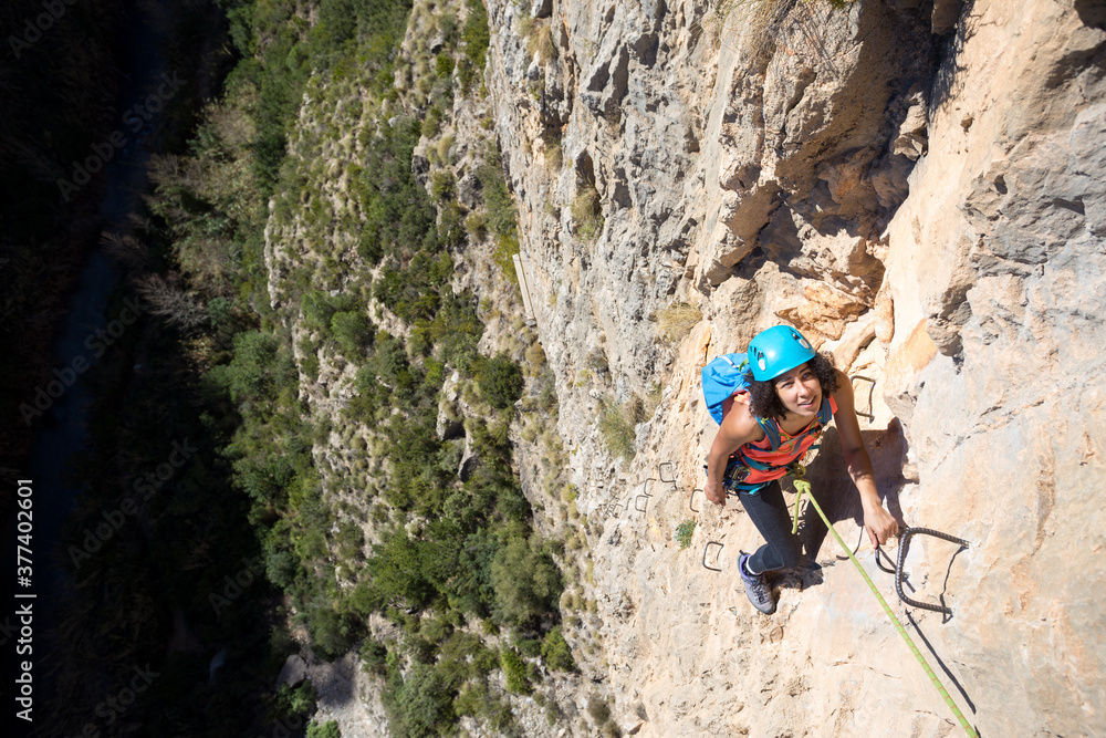 Young woman climbing through a via ferrata in Chulilla Canyon (Spain) Young woman climbing through a via ferrata in Chulilla Canyon (Spain)