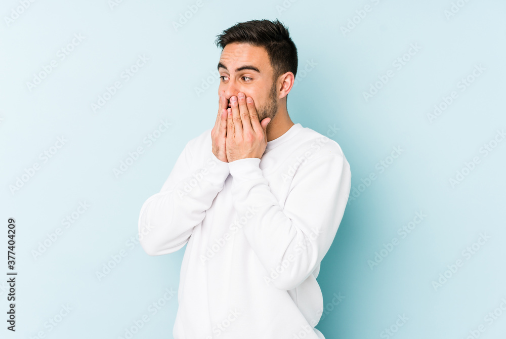 Young caucasian man isolated on blue background laughing about something, covering mouth with hands. Young caucasian man isolated on blue background laughing about something, covering mouth with hands.