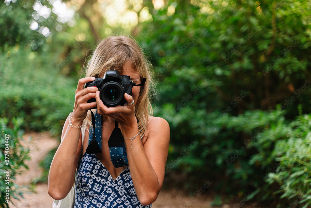 Woman taking a picture standing in a park Woman taking a picture standing in a park
